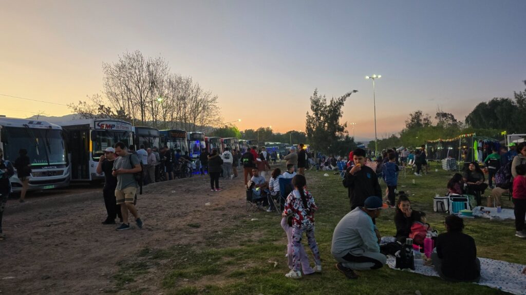Colectivos alineados y público en el parque al atardecer