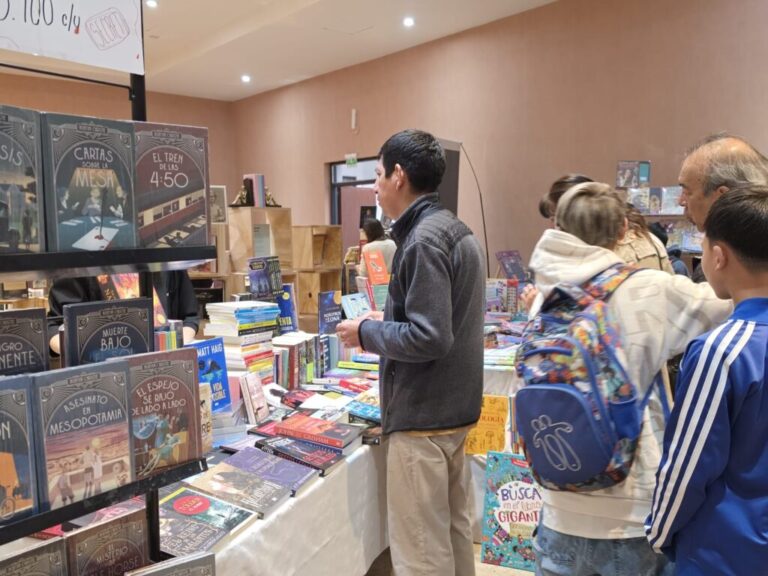Estante con libros de Agatha Christie y público en la Feria del Libro