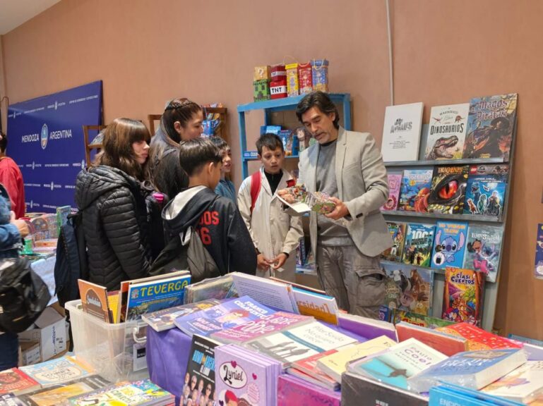 Chicos y un expositor revisan libros durante la Feria del Libro