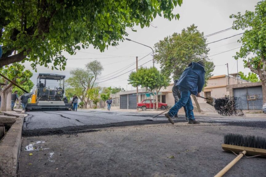 Operario con pala junto a la terminadora de asfalto