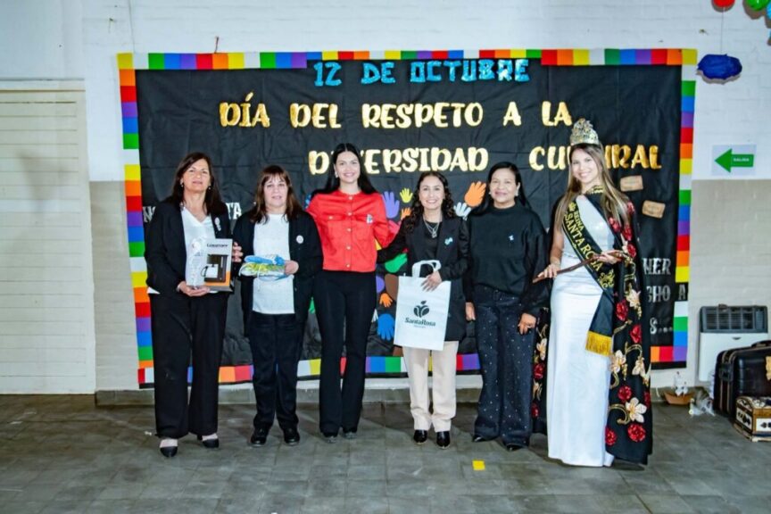 Autoridades posan junto al cartel del 12 de Octubre con obsequios